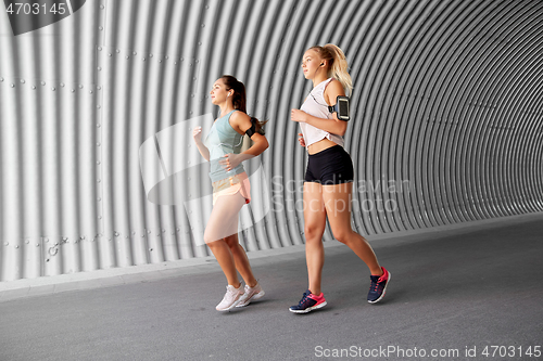 Image of young women with earphones and smartphones running