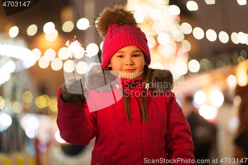 Image of happy girl with sparkler at christmas market