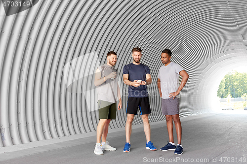 Image of sporty men or friends with smartphone in tunnel