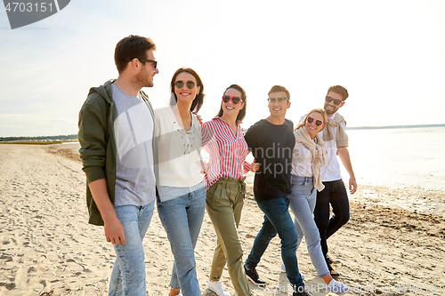 Image of happy friends walking along summer beach