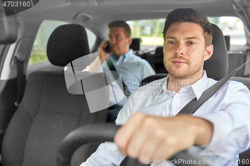 Image of male taxi driver driving car with passenger