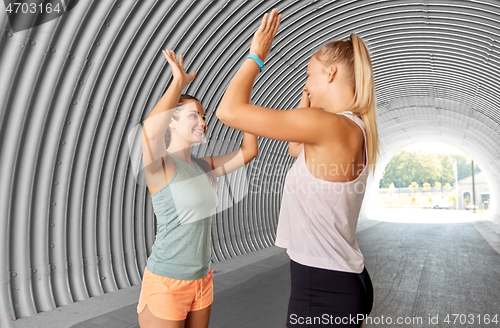Image of happy women with fitness trackers making high five