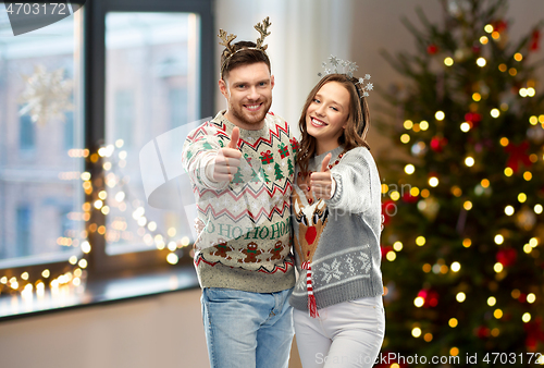 Image of couple in christmas ugly sweaters shows thumbs up