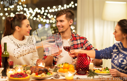 Image of happy friends drinking red wine at christmas party