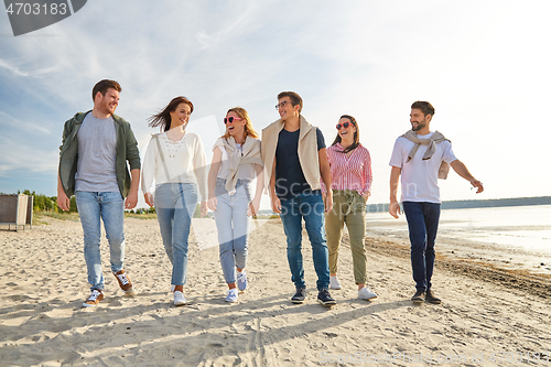 Image of happy friends walking along summer beach