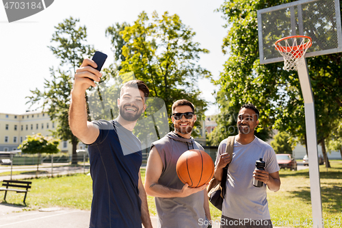 Image of happy men taking selfie at basketball playground