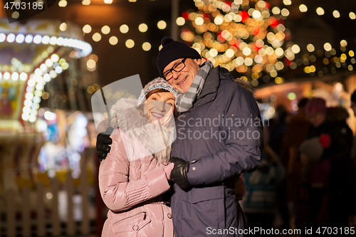 Image of happy senior couple hugging at christmas market