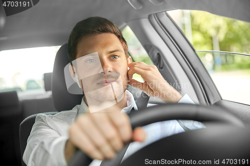 Image of man or driver with wireless earphones driving car