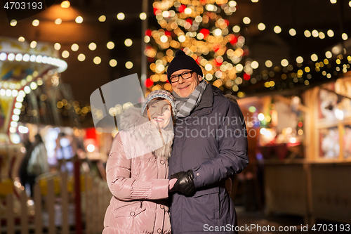 Image of happy senior couple hugging at christmas market