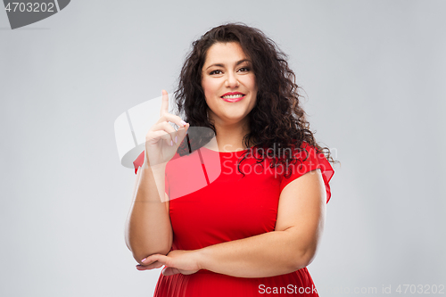 Image of happy woman in red dress pointing finger up