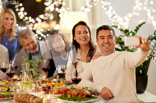 Image of family having dinner party and taking selfie