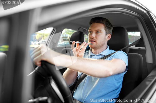 Image of man driving car and recording voice by smartphone