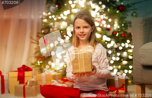 Image of smiling girl with christmas gift at home