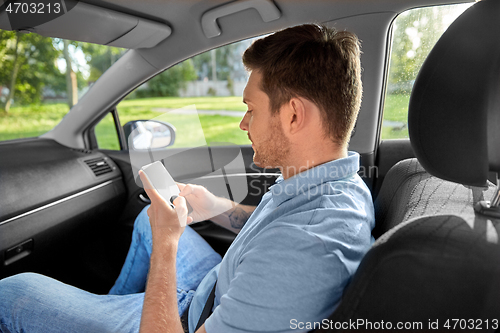 Image of male passenger using smartphone in taxi car