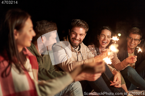Image of happy friends with sparklers at night outdoors