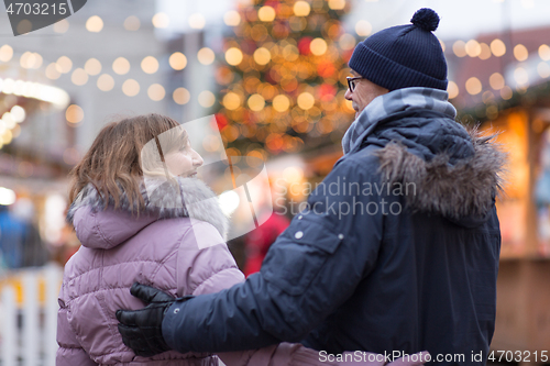 Image of happy senior couple hugging at christmas market