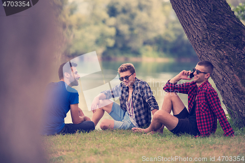 Image of men sitting on the bank of the river