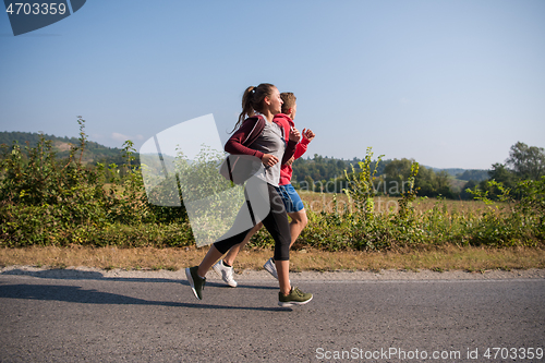 Image of young couple jogging along a country road
