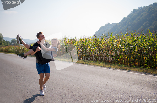 Image of happy couple jogging along a country road