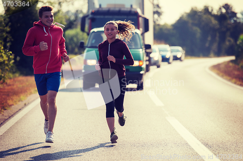 Image of young couple jogging along a country road