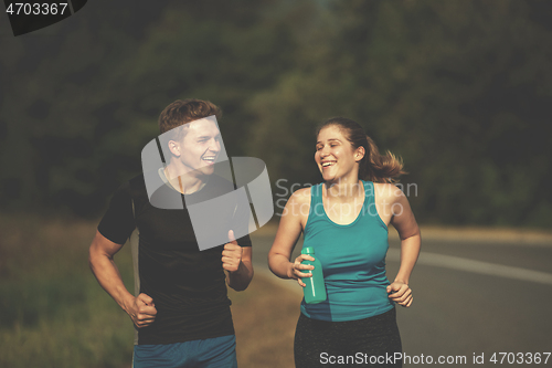 Image of young couple jogging along a country road