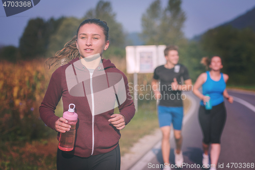 Image of young people jogging on country road