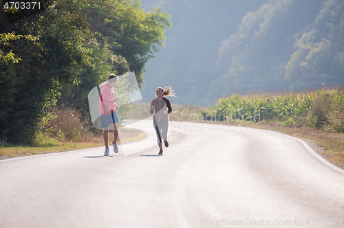 Image of young couple jogging along a country road