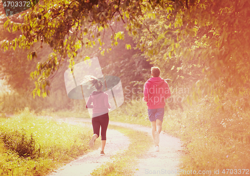 Image of young couple jogging along a country road