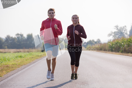 Image of young couple jogging along a country road