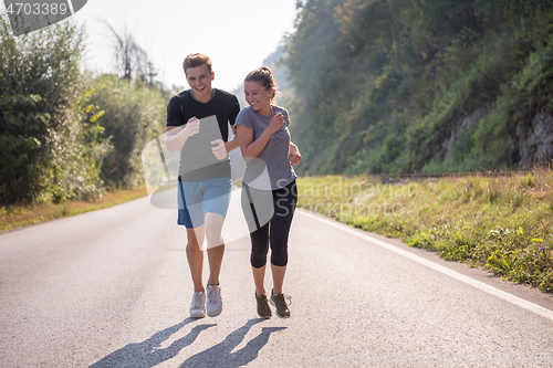 Image of young couple jogging along a country road