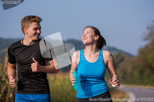 Image of young couple jogging along a country road