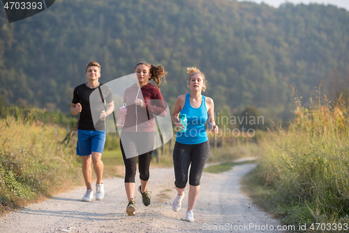 Image of young people jogging on country road