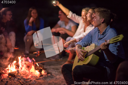 Image of young friends relaxing around campfire