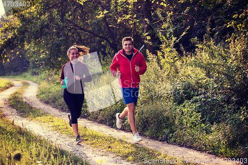 Image of young couple jogging along a country road