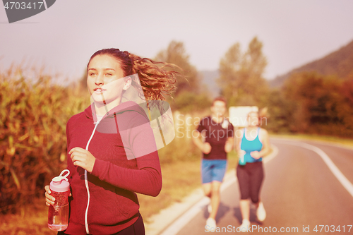 Image of young people jogging on country road