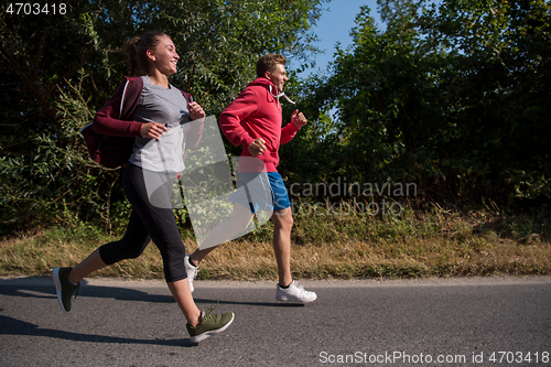 Image of young couple jogging along a country road