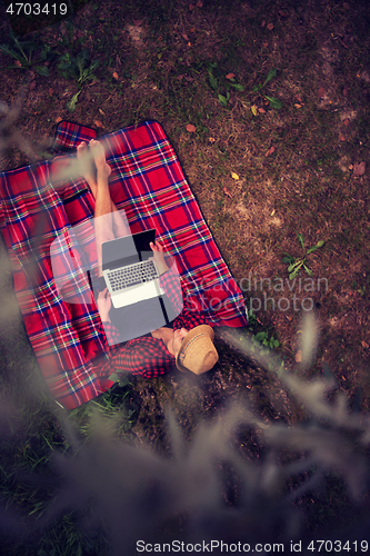 Image of top view of man using a laptop computer under the tree