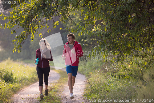 Image of young couple jogging along a country road