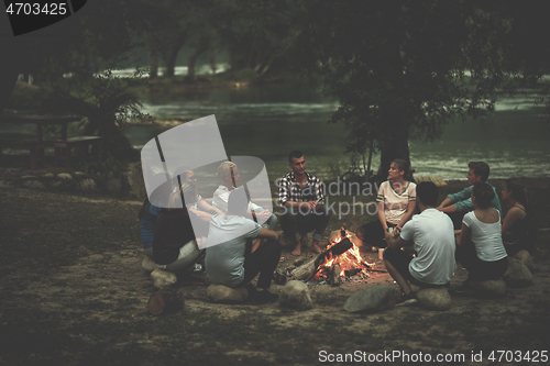 Image of young friends relaxing around campfire