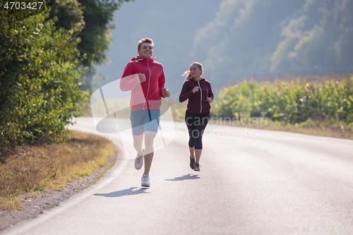 Image of young couple jogging along a country road