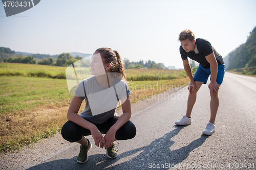 Image of young couple warming up and stretching on a country road