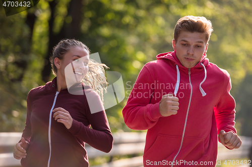 Image of young couple jogging along a country road