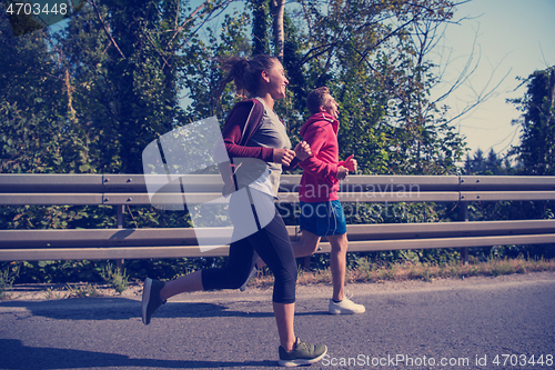 Image of young couple jogging along a country road