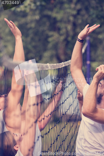 Image of group of young friends playing Beach volleyball