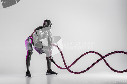 Image of Young african-american bodybuilder training over grey background