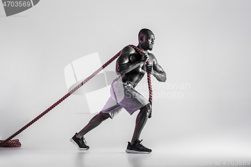 Image of Young african-american bodybuilder training over grey background