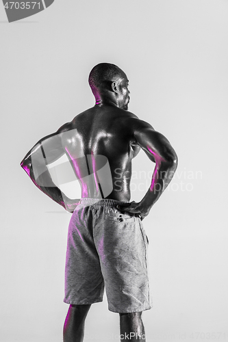 Image of Young african-american bodybuilder training over grey background