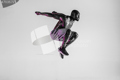 Image of Young african-american bodybuilder training over grey background