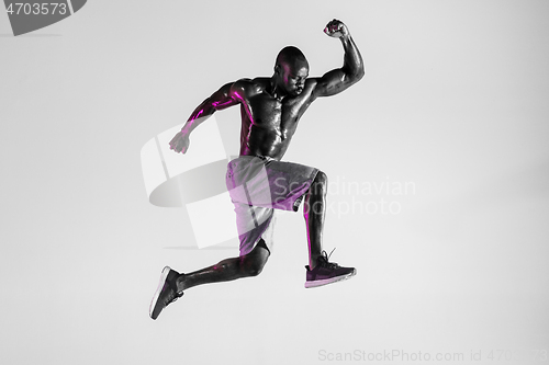 Image of Young african-american bodybuilder training over grey background