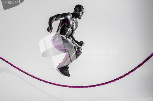 Image of Young african-american bodybuilder training over grey background